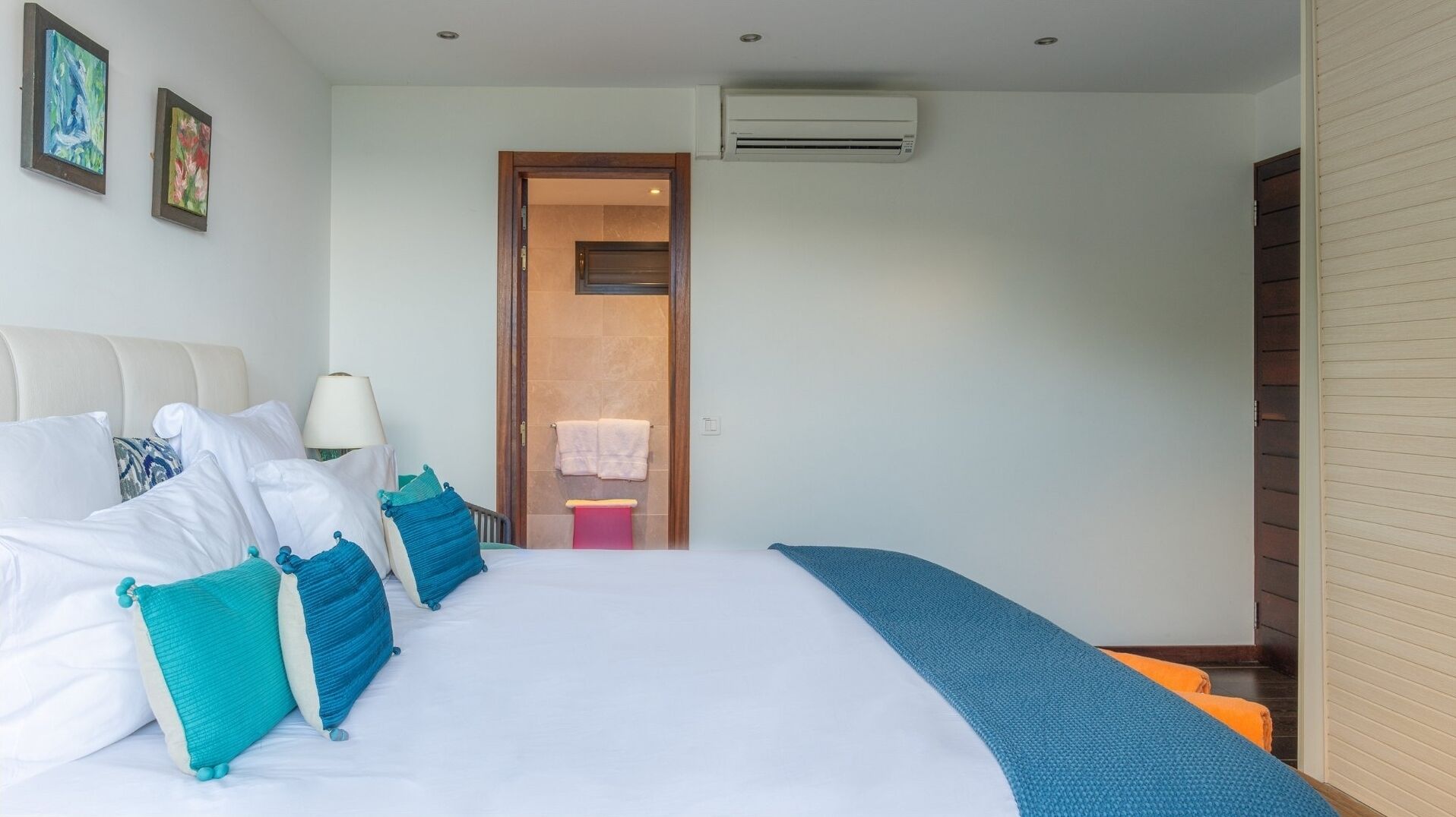 Et hotelværelse med en stor seng, et sengebord, en lampe og en aircondition.