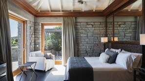 Een moderne slaapkamer met een stenen muur, een groot bed, een bank en een kleine tafel.