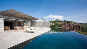 A modern outdoor pool area with lounge chairs and a stone building.