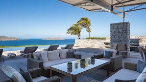 An outdoor patio with wicker furniture, a stone pillar, and a view of the sea.