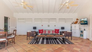 A spacious bedroom with a large bed, two nightstands, a TV, and a bookshelf. - Alizee d'Eden (1/2 Rooms) (Pointe Milou)