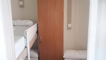 Een kleine kamer met twee bedden, een houten deur en een witte radiator.