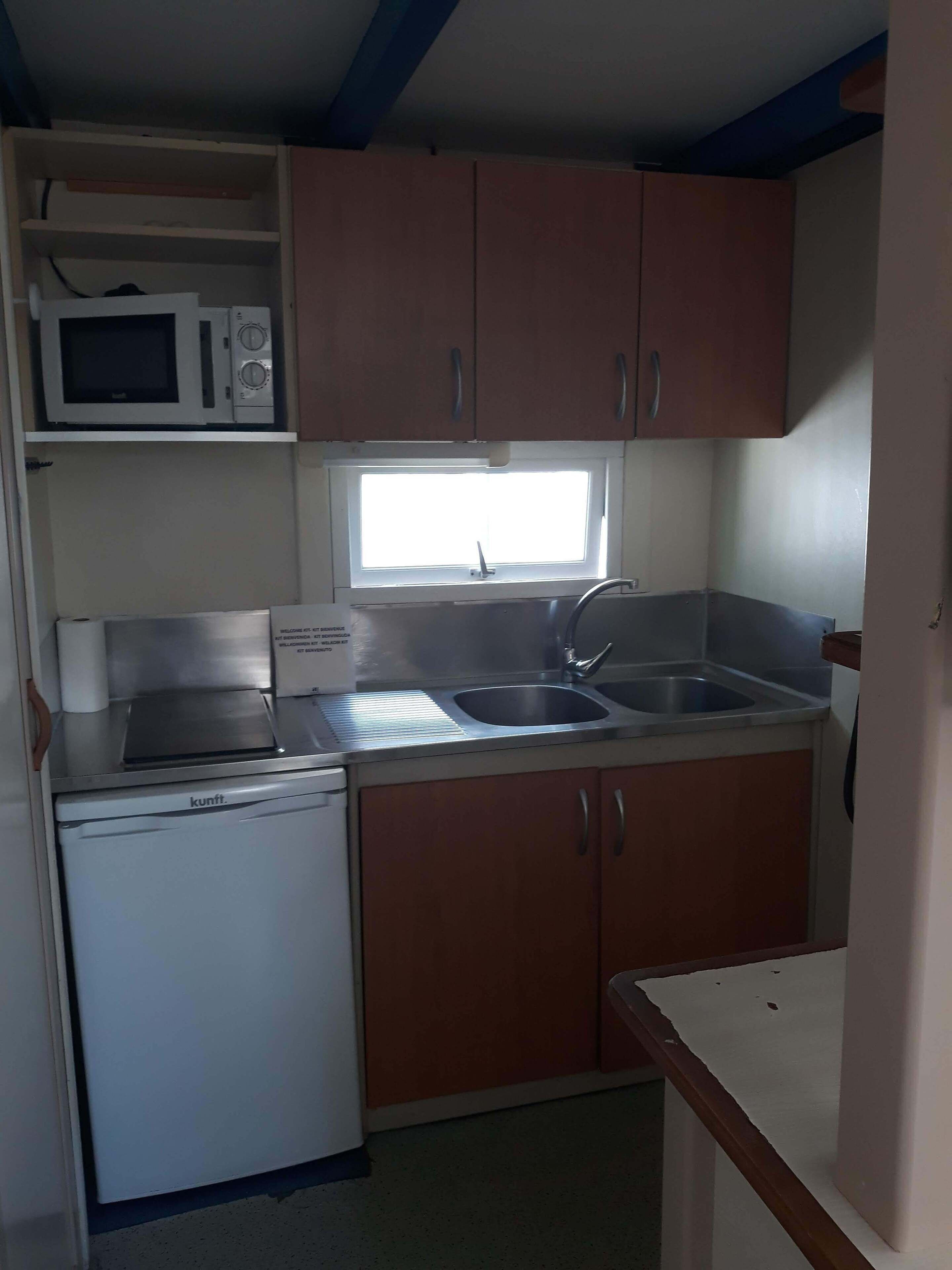 A compact kitchen with a microwave, a toaster, a sink, and a dishwasher.
