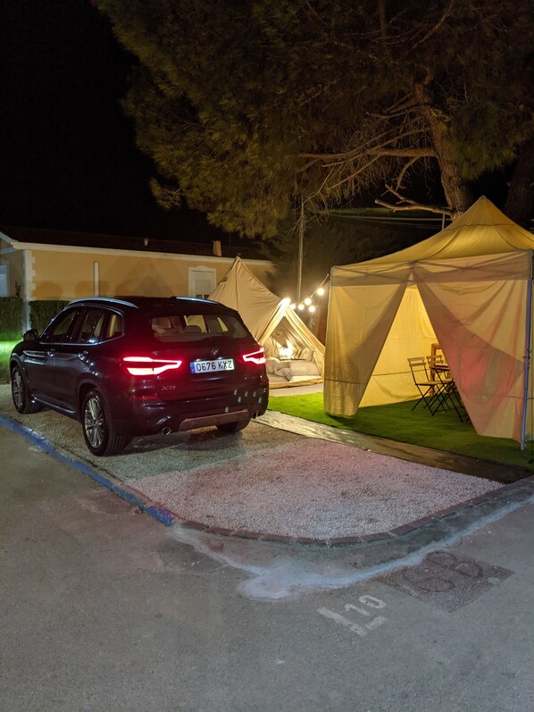 Un SUV rojo estacionado en un estacionamiento con una tienda de campaña y un conjunto de mobiliario de exterior cerca.