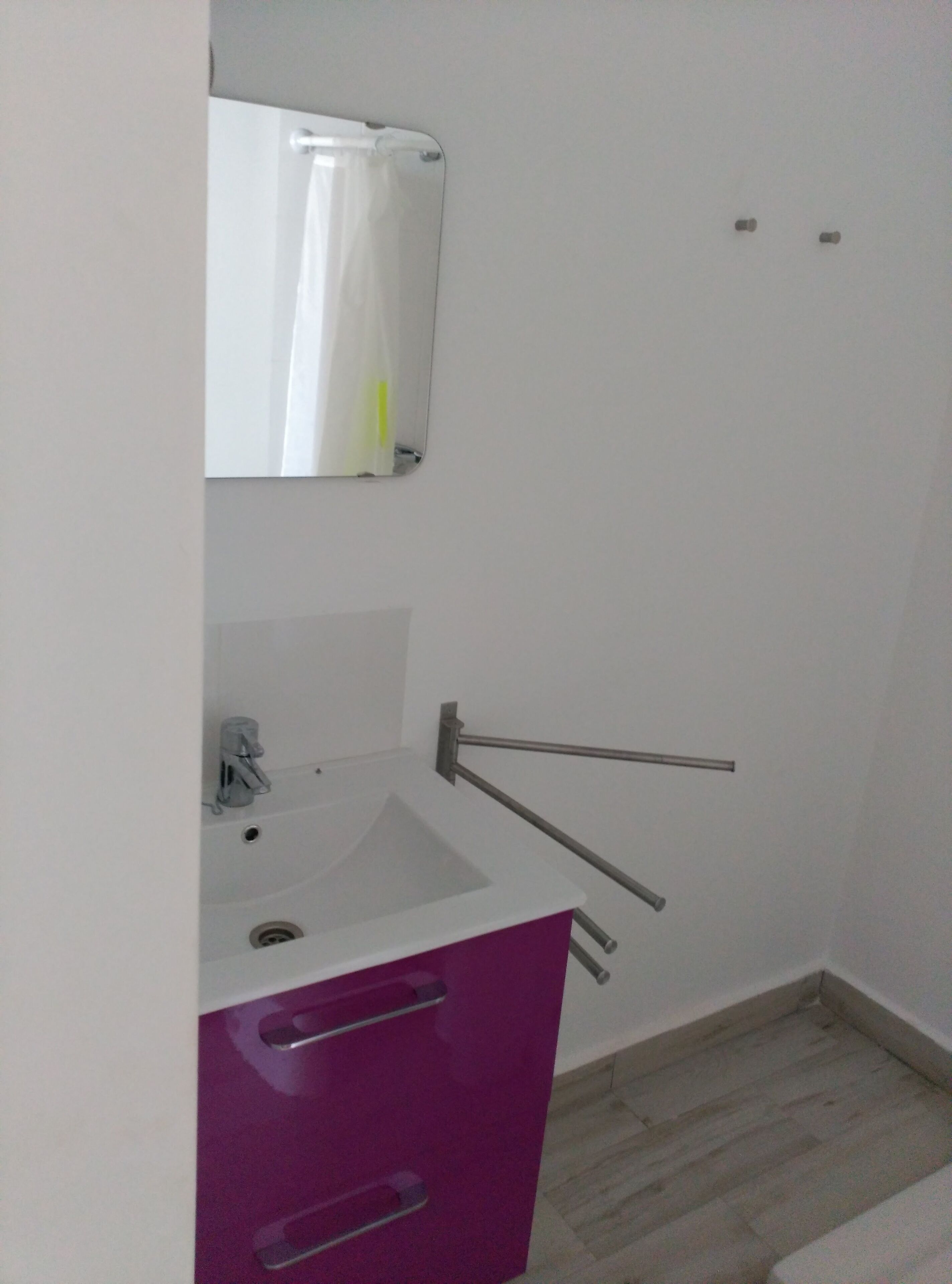 Kylpyhuoneessa on valkoinen pesuallas, peili ja violetti kaappi.