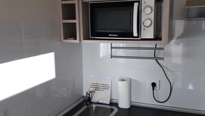 A compact kitchenette with a microwave, a small sink, and a built-in dishwasher. - camping san javier (San Javier)