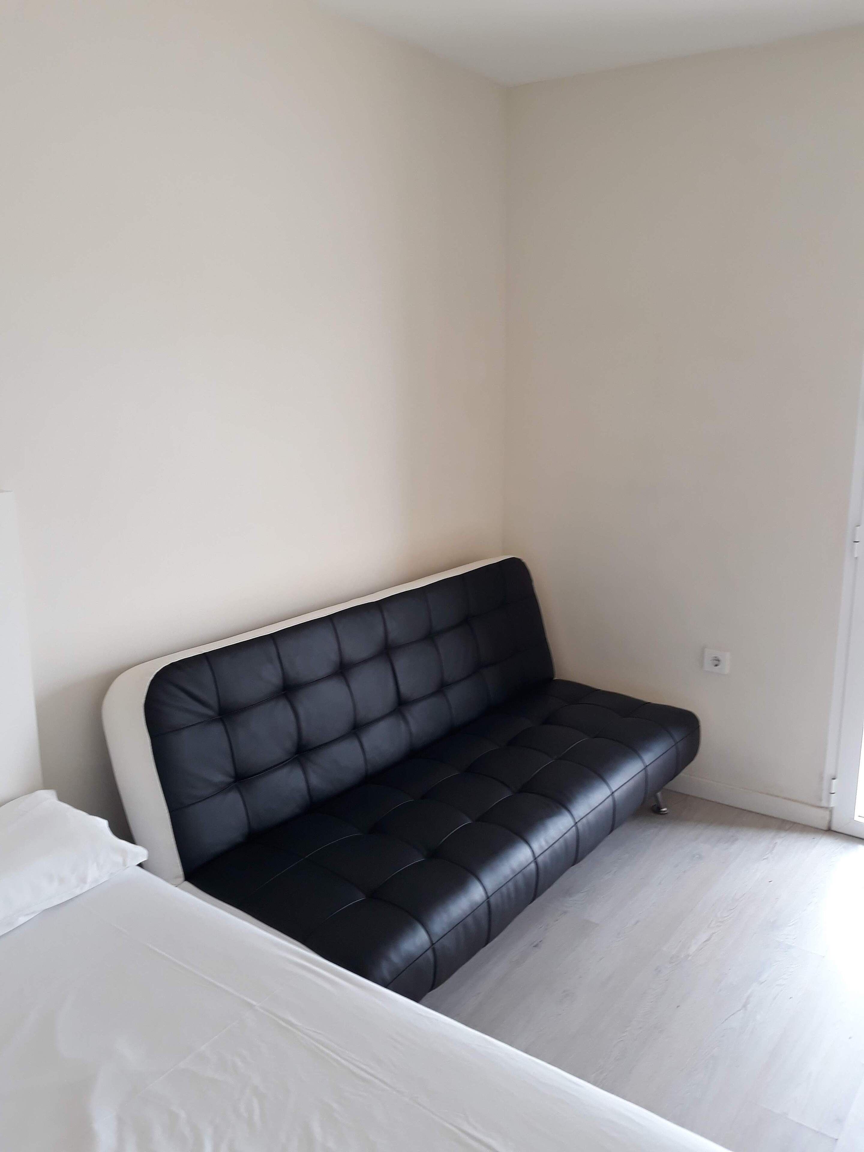 Ein schwarzes Ledersofa in einem Raum mit weißen Wänden und einem weißen Boden.