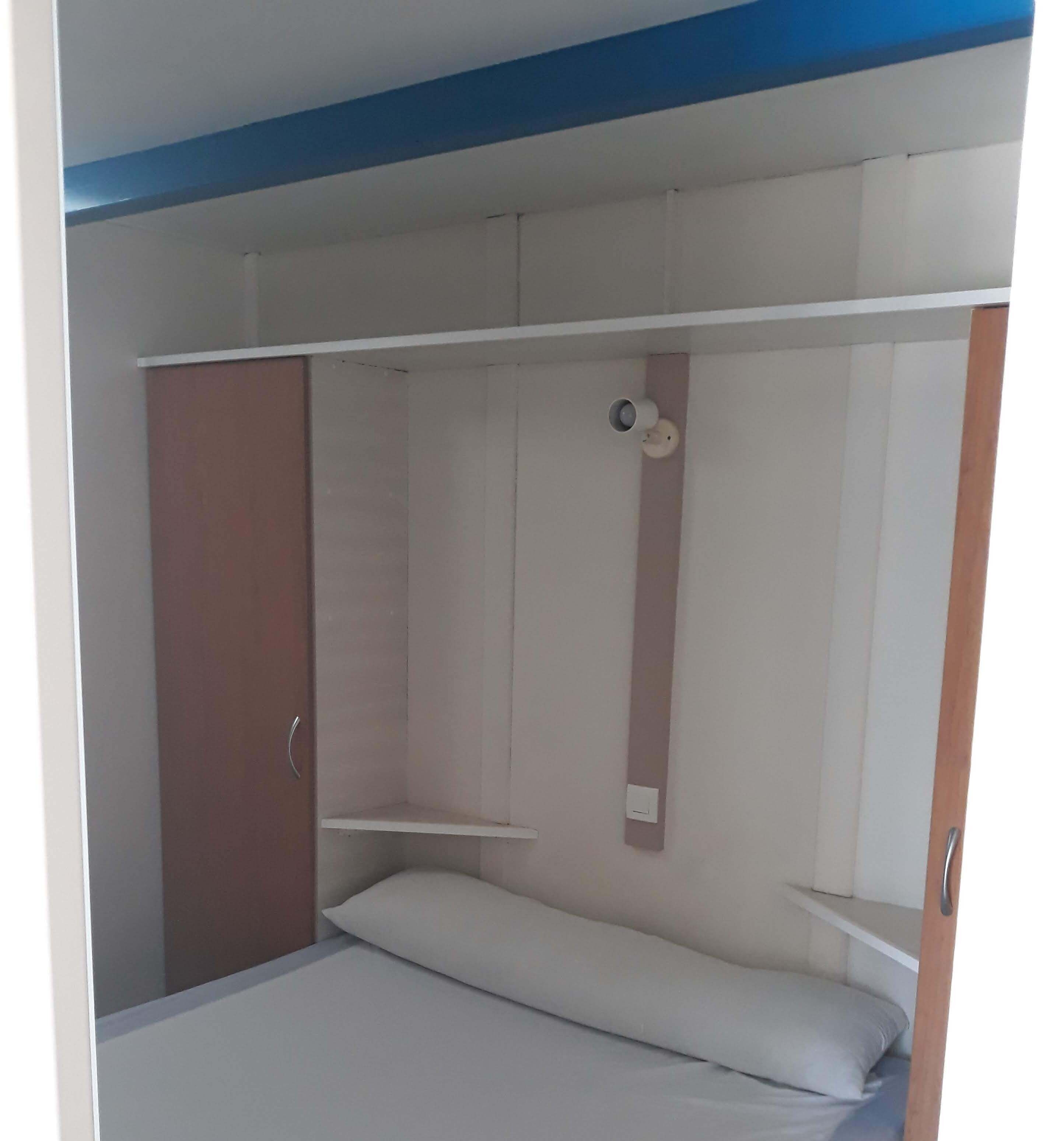 Quarto com uma cama, guarda-roupa e estante.