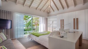 A modern bedroom with a bed, a desk, a TV, and a view of the outdoors. - Wings (2/4 Rooms) Luxury villa (Saint Jean)