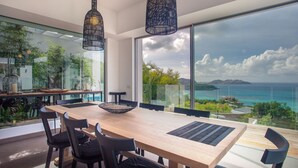Un comedor moderno con una mesa grande, sillas negras y vistas al océano.