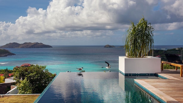 Uma piscina infinita com vista para o oceano e ilhas distantes.