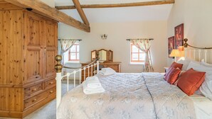 Ein Schlafzimmer mit einem großen Bett, einem Holzschrank und einem Fenster mit Vorhängen.