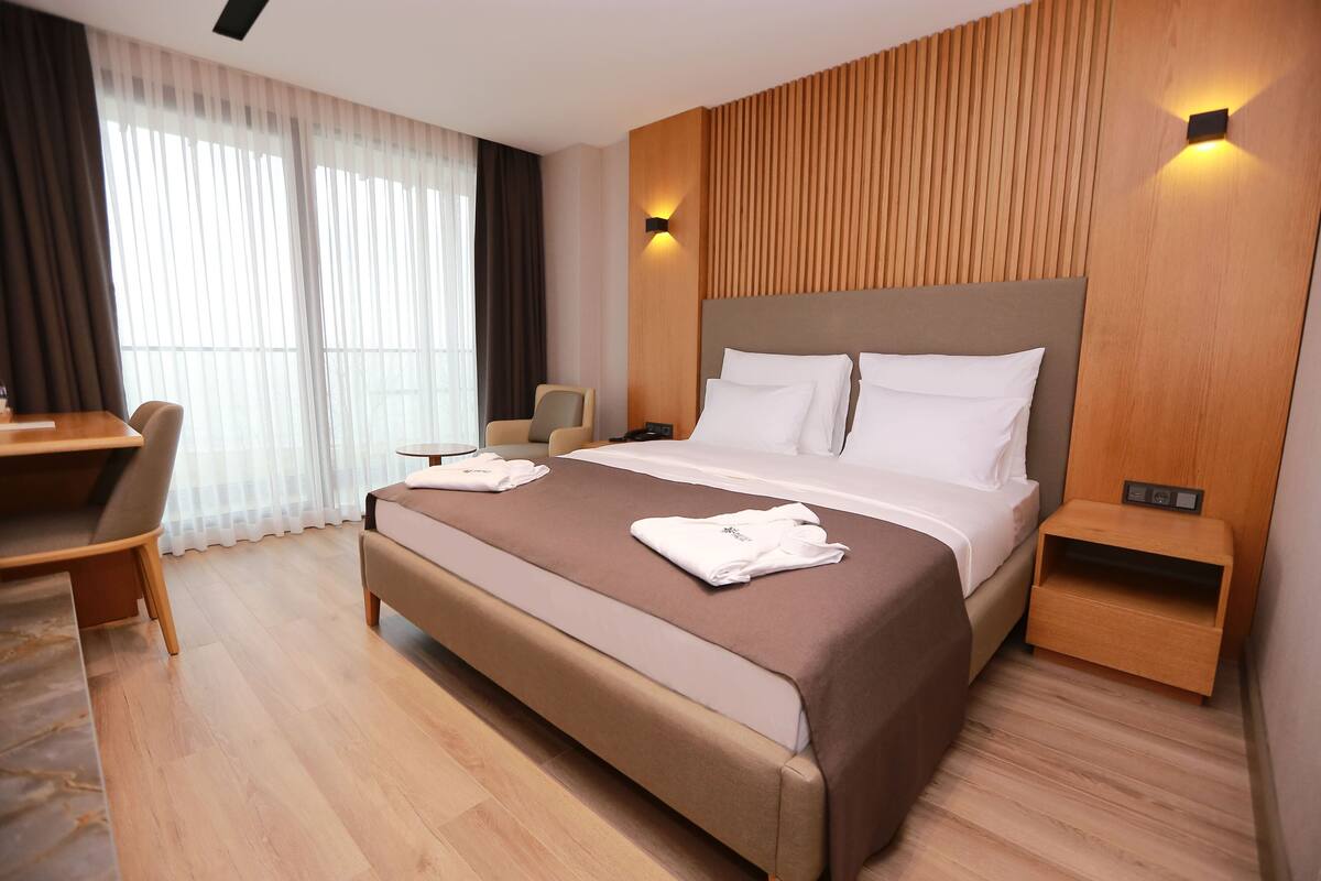 Quarto de hotel moderno com uma cama grande, uma escrivaninha e uma cadeira.