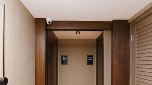 A hallway with a wooden door on the right, a security camera on the ceiling, and two signs indicating room numbers 301 and 302. - Pikola Otel (Ordu)
