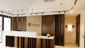 A reception desk with a marble top, a logo, and a wall-mounted light fixture. - Pikola Otel (Ordu)