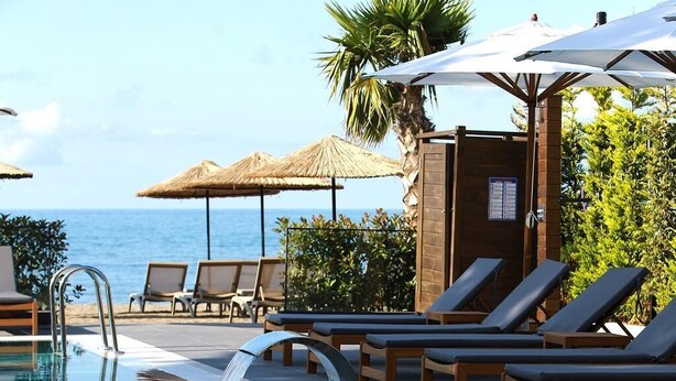 A pool area with lounge chairs and umbrellas, a clear view of the ocean, and a thatched umbrella structure. - Pikola Otel (Ordu)