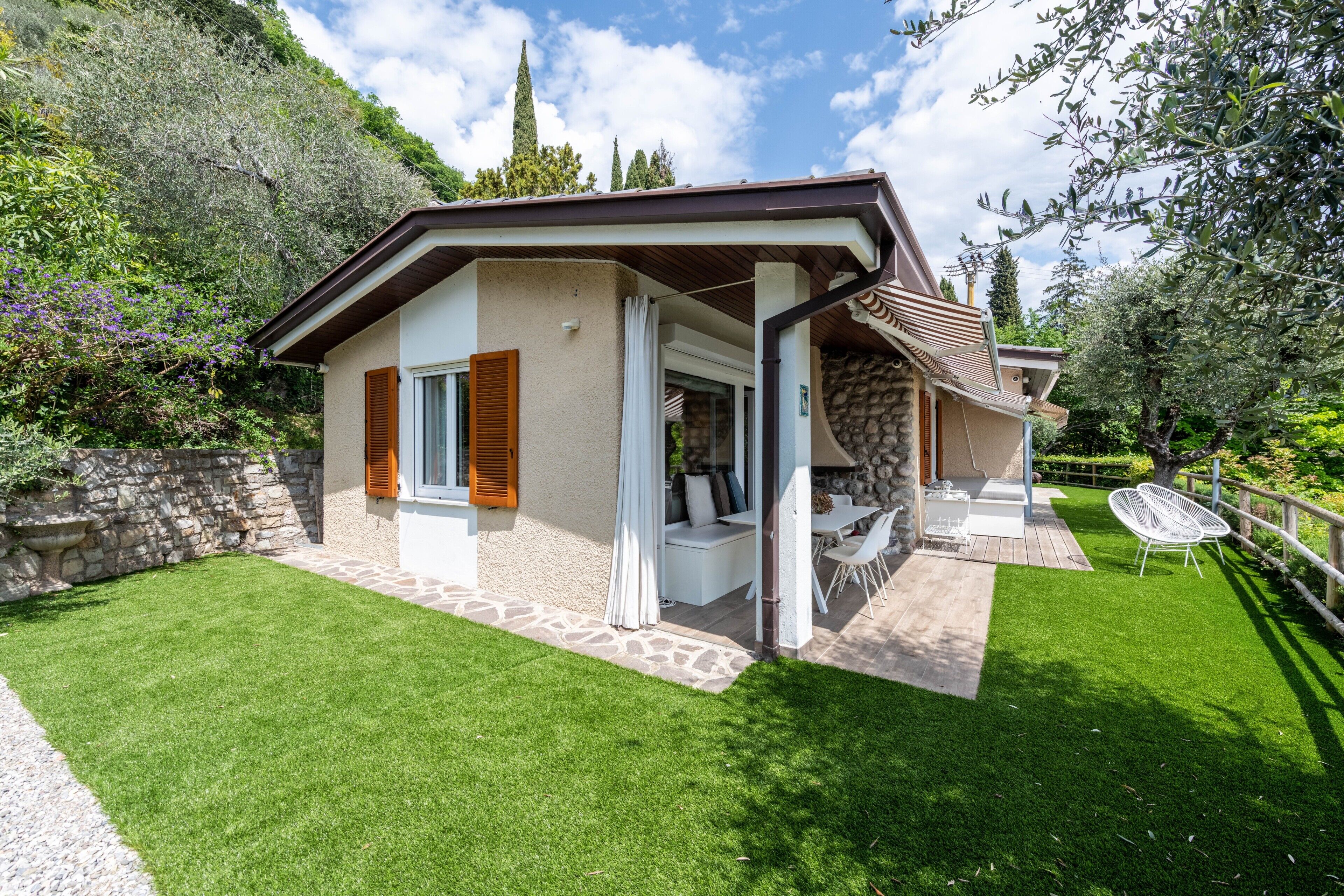 Ein Haus mit Steinverkleidung, einer überdachten Terrasse und einem gepflegten Rasen.