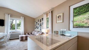 A modern kitchen with a central island, a dining area with a white table and chairs, and a living area with a sofa and a coffee table. - Apartment "Casa 50" with Garden & Shared Pool (Gargnano)