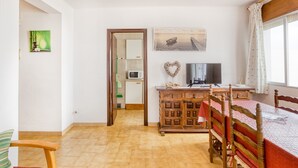 Una habitación con una mesa de comedor de madera, sillas, un televisor, un armario y una ventana con cortinas.