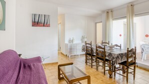 A dining area with a table set for four, a sofa, and a glass coffee table. - Apartment on the Paseo Marítimo '1-3' close to the Beach with Terrace & Wi-Fi (Llançà)