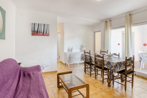 Un coin repas avec une table dressée pour quatre personnes, un canapé et une table basse en verre.