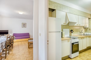 Une cuisine avec des meubles blancs, une cuisinière, un four à micro-ondes et un évier.