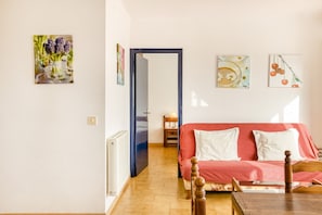 A room with a red sofa, a wooden table, and a door leading to another room.