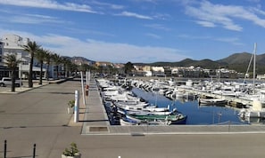 A marina with numerous boats docked, a clear sky, and buildings in the background.