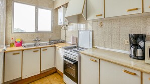 A kitchen with white cabinets, a stove, a sink, and a window. - Apartment 'Mediterranean View 3-1' close to the Beach with Terrace & Wi-Fi (Llançà)