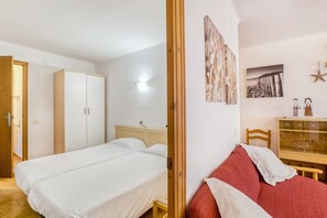 A bedroom with a bed, a wardrobe, a desk, and a chair.