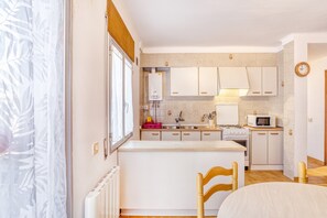 A compact kitchen with white cabinets, a stove, a microwave, and a sink.