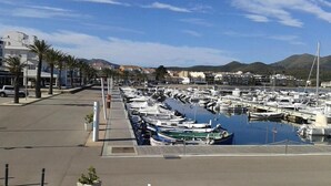 A marina with numerous boats docked, a clear sky, and buildings in the background.