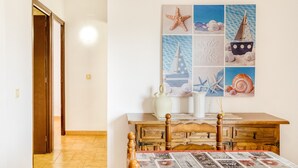A room with a wooden table, a chair, a wall with a nautical-themed artwork, and a door leading to another room.