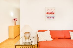 Une pièce comprenant un lit, une lampe, une petite table, un meuble et une œuvre d’art accrochée au mur.