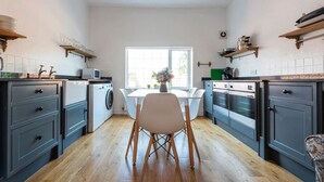 Une cuisine compacte dotée d’un îlot central, d’appareils électroménagers intégrés et d’une fenêtre laissant entrer la lumière naturelle.