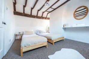 A bedroom with two wooden beds, a round mirror, and a small shelf with towels. - Riverside Rest - quirky split-level 3-bed cottage (Ollerton, Nottinghamshire)