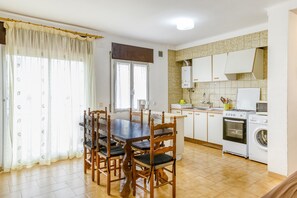 A kitchen with a dining table, chairs, a stove, an oven, and a washing machine.