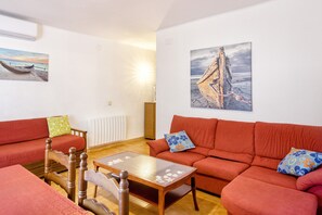 Ein Wohnzimmer mit einer Couch, einem Holztisch und zwei Bildern an der Wand.