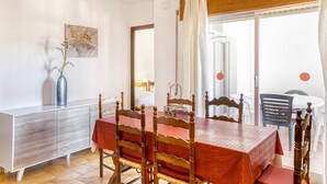 Ein Essbereich mit Tisch, Stühlen, einem Schrank und Blick durch ein Fenster.