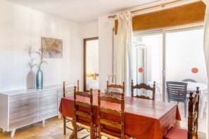 A dining area with a table, chairs, a cabinet, and a view through a window.