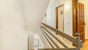 Eine Holztreppe mit Geländer führt zu einer Tür mit Glasfenster.