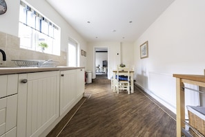 A kitchen with white cabinets, a wooden countertop, and a window with blinds.