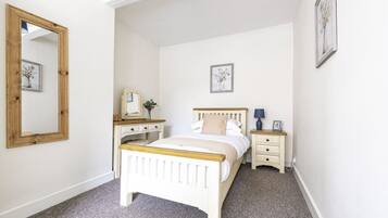 A bedroom with a bed, bedside tables, a dresser, and a mirror.