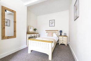 A bedroom with a bed, bedside tables, a dresser, and a mirror. - Ropemaker's Cottage, · Ropemaker's Cottage, cosy cottage retreat (Ollerton, Nottinghamshire)