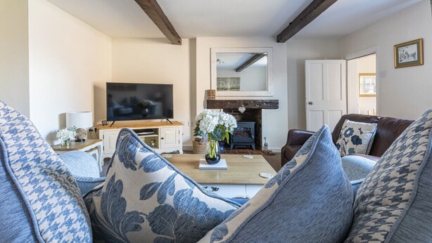A living room with a sofa, a coffee table with a vase, a television, and a fireplace. - Ropemaker's Cottage, · Ropemaker's Cottage, cosy cottage retreat (Ollerton, Nottinghamshire)