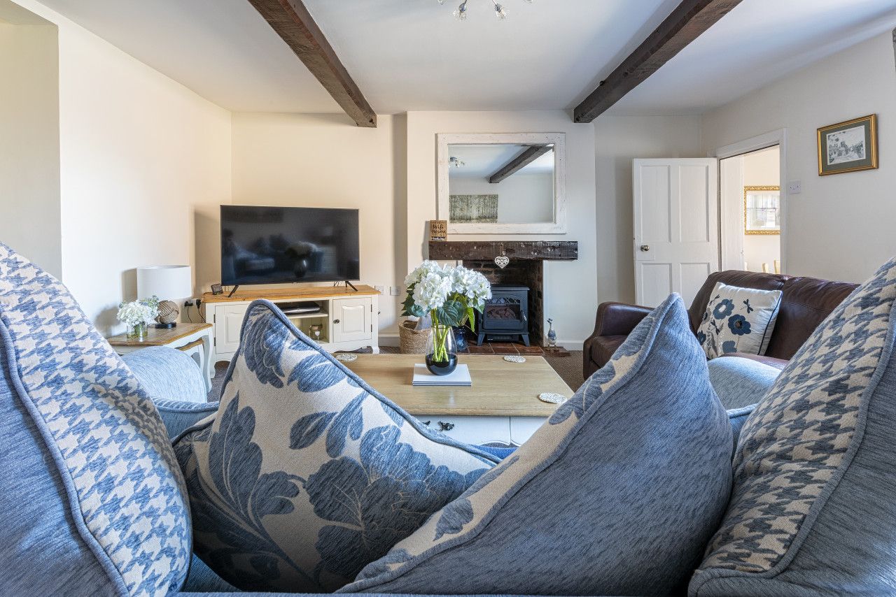 A living room with a sofa, a coffee table with a vase, a television, and a fireplace.