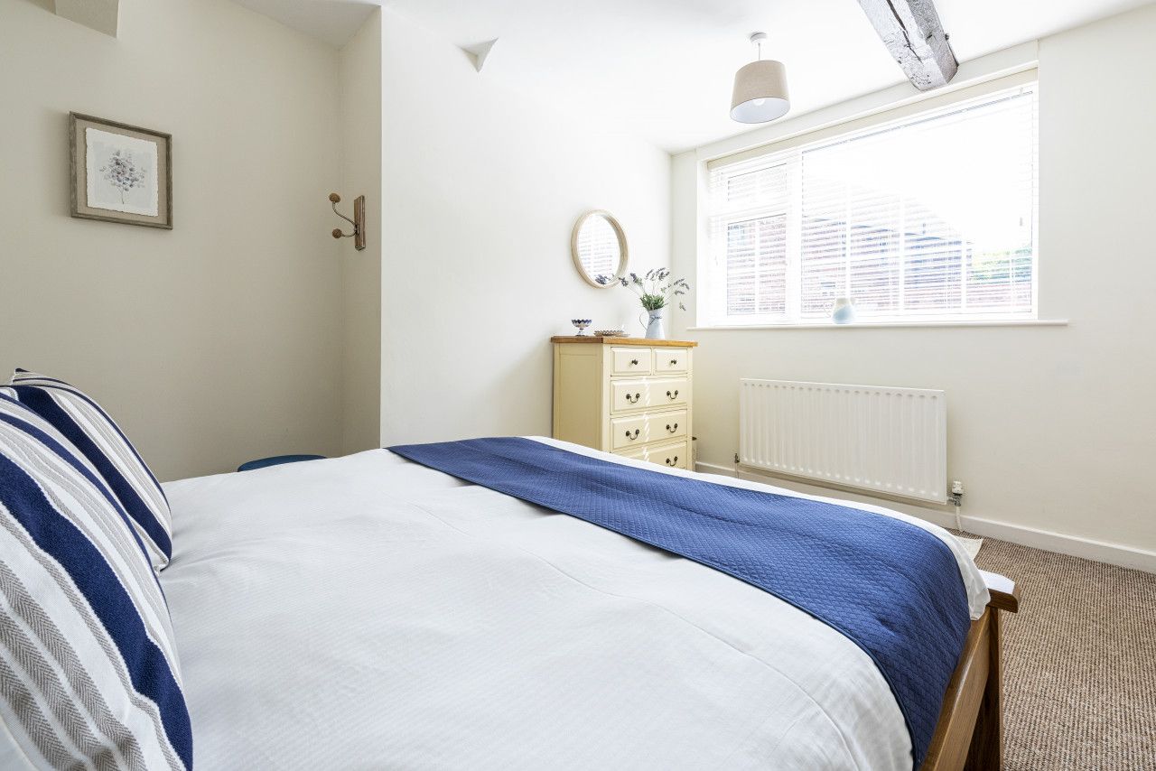 A bedroom with a bed, a dresser, a window, and a radiator.