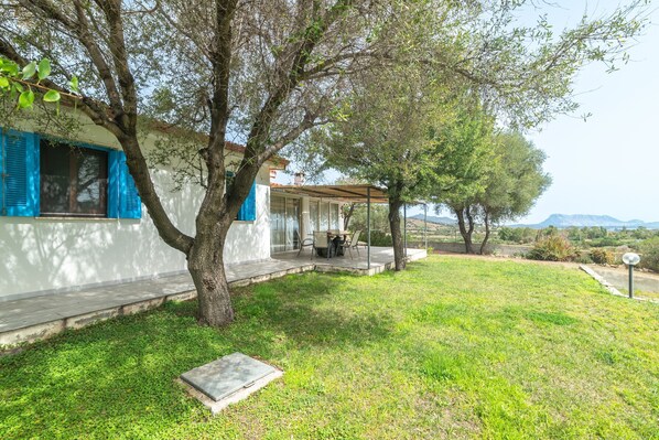 A house with a covered patio, a lawn, and a view of distant mountains.