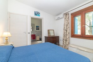 Une chambre à coucher comprenant un lit, une commode, un miroir, une fenêtre avec des rideaux et un appareil de climatisation.