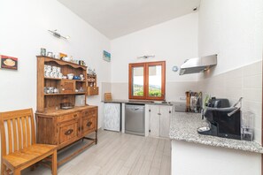 Une cuisine avec des meubles en bois, un lave-vaisselle, une machine à café et une fenêtre donnant sur un beau paysage.